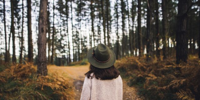 Woman with hat walking in the woods.