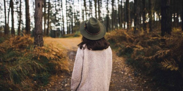 Woman with hat walking in the woods.