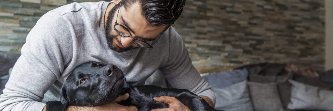 What It's Like to Have Both Autism and ADHD Man cuddling with his dog on the couch at home