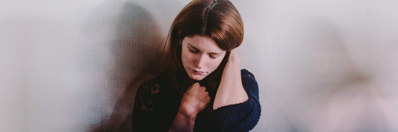 Advice for Anyone Newly Diagnosed With Anxiety photo of a young person against a wall looking anxious with blurred figures all around