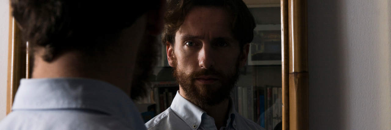 Here's Your 'Permission' to Change Your Name Due to Trauma (or Any Other Reason) photo of a bearded man looking into a mirror