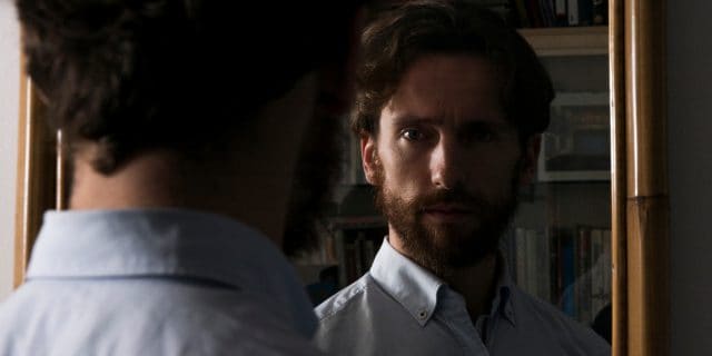photo of a bearded man looking into a mirror