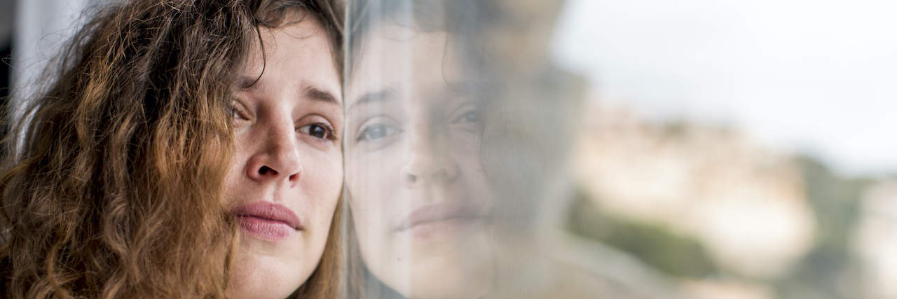 Realizing My Bipolar Anger Was Really Grief Woman with sad expression leaning against a window
