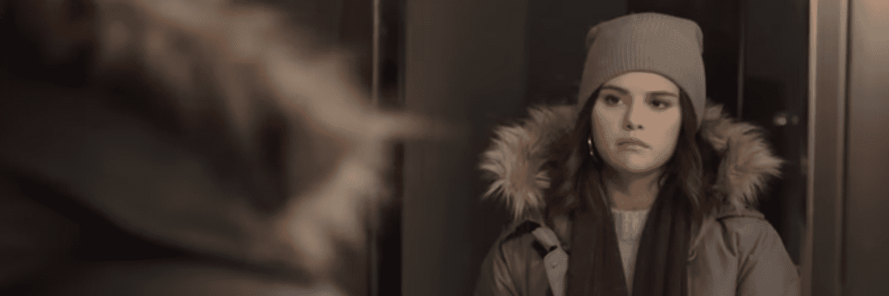 'Only Murders in the Building' Explains Dissociation Perfectly Selena Gomez in a winter jacket and beanie looking at herself in the mirror, serious expression