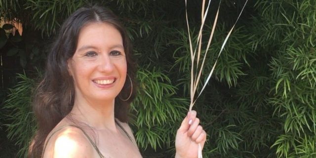 Why I Always Try to Make My Birthday the Ultimate Self-Care Day The author stands outside wearing a gold dress with spaghetti straps and holding pink and white balloons.