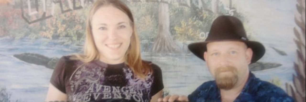 What My Marriage Looks Like as a Disabled Woman Married to a Non-Disabled Man The author sits in a wheelchair next to her husband. They are jointly holding a gator.