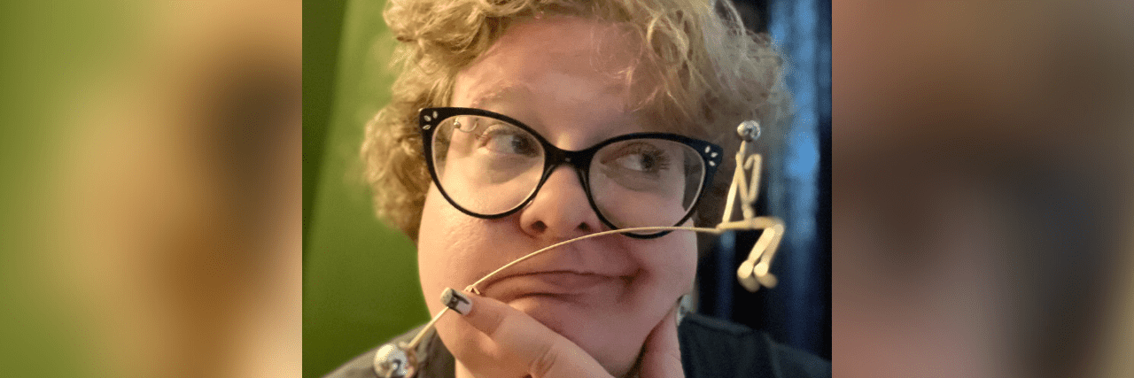 Learning to Live in the Middle Place for My Physical and Mental Health Image of contributor looking to the side, holding a perpetual motion device with a ball on one side and shape of a person on the other