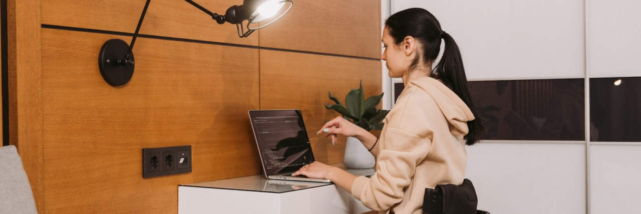 14 Ways to Enhance Accessibility and Well-Being With Home Renovations Woman in wheelchair working at desk.