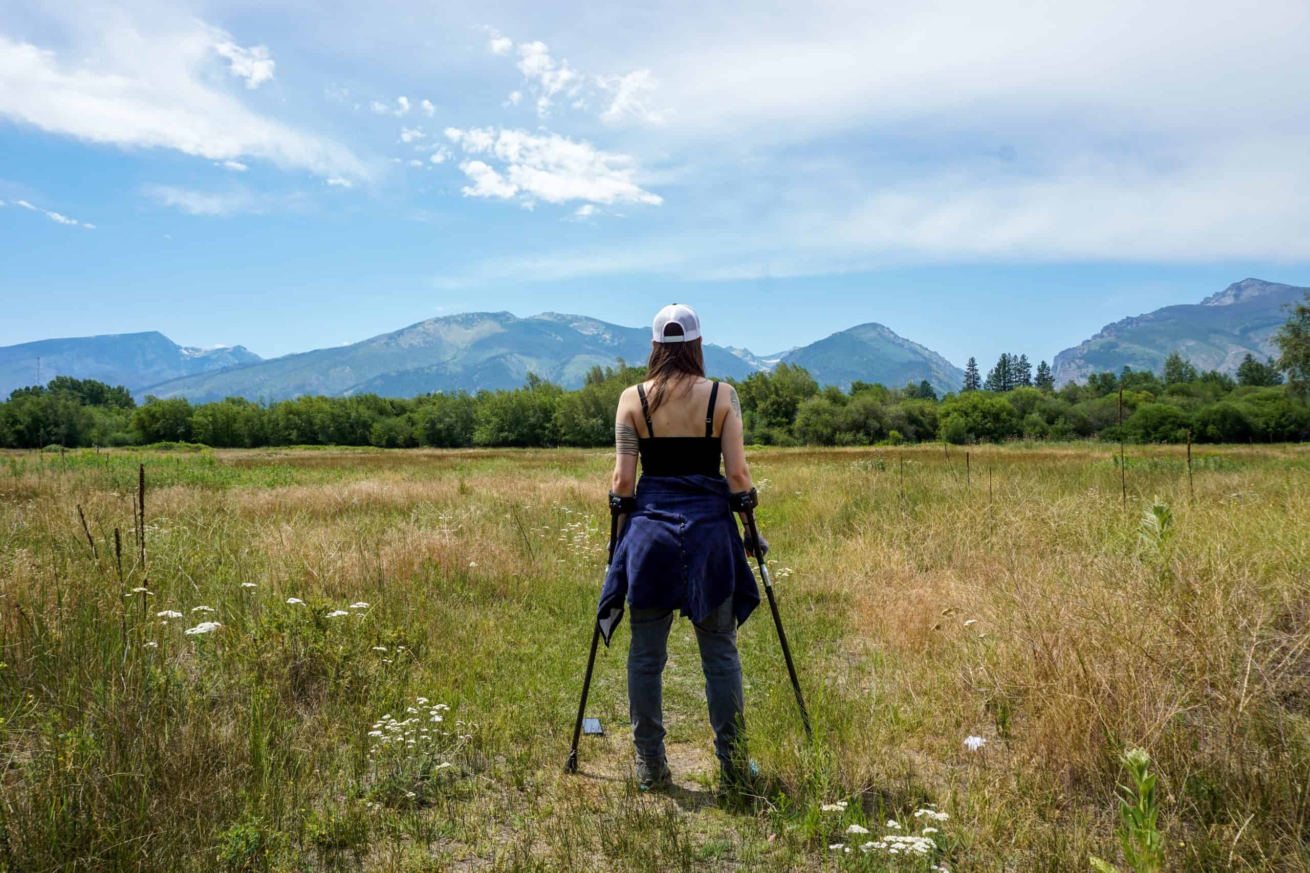 Contributor standing with walking sticks, in front of mountain view on horizon