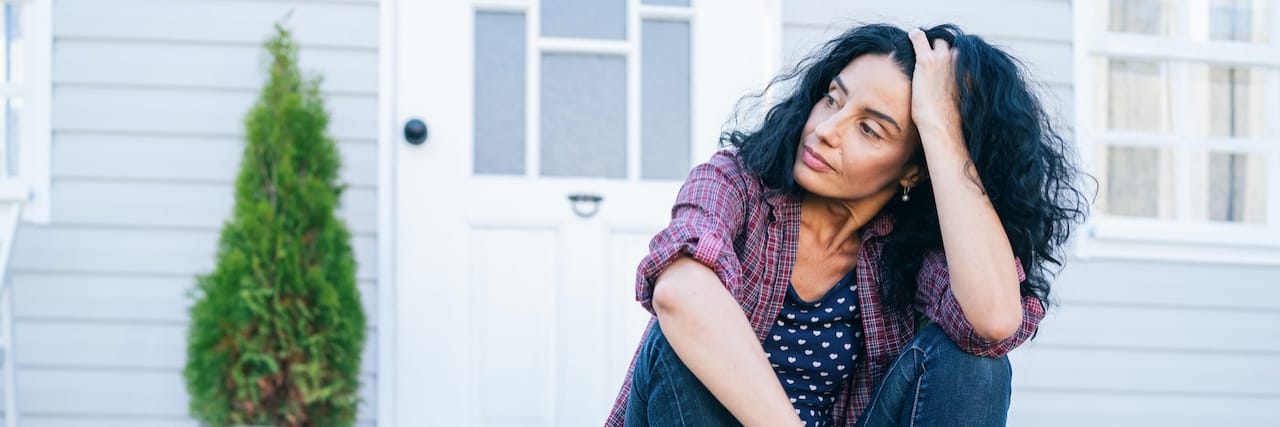 Guidance on Cancelling a Therapy Session Woman sitting on stairs in front of house