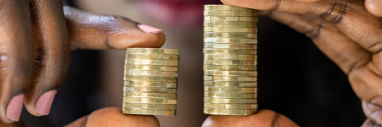 What You Need to Hear if Your Anxiety Is Stopping You From Negotiating Your Salary A Black woman holding two sets of coins one set that is larger and one is smaller