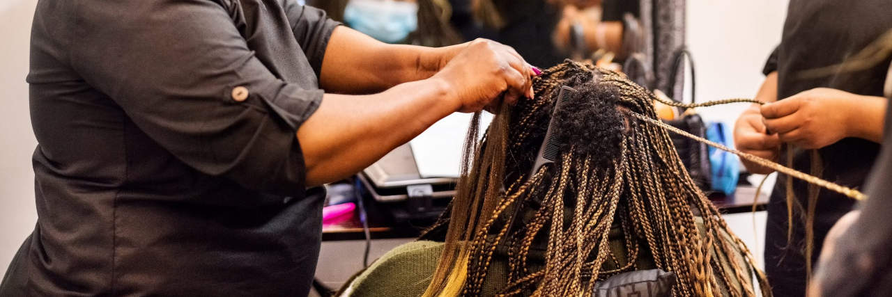 How One Woman Uses Beauty Salons to Cope With C-PTSD Hairstylists braiding and extending a client's hair in salon