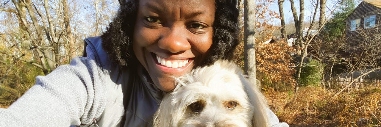 Close-up of mid adult black woman in selfie outdoors with her Coton de Tuléar