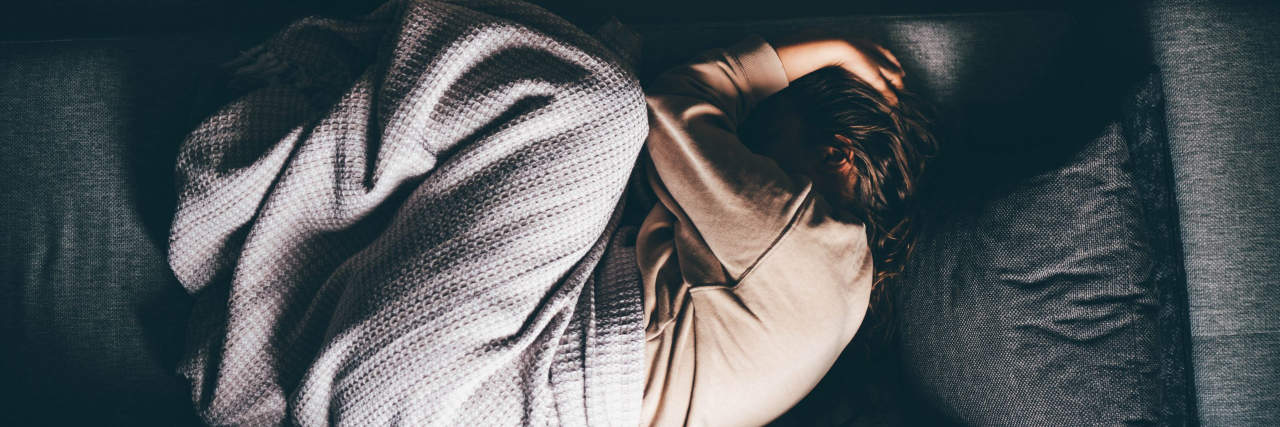 What You Should Know if You've Been Newly Diagnosed With Chronic Fatigue Syndrome Worried young woman lying on sofa at home.
