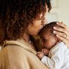 Black mother holding and kissing baby on top of their head