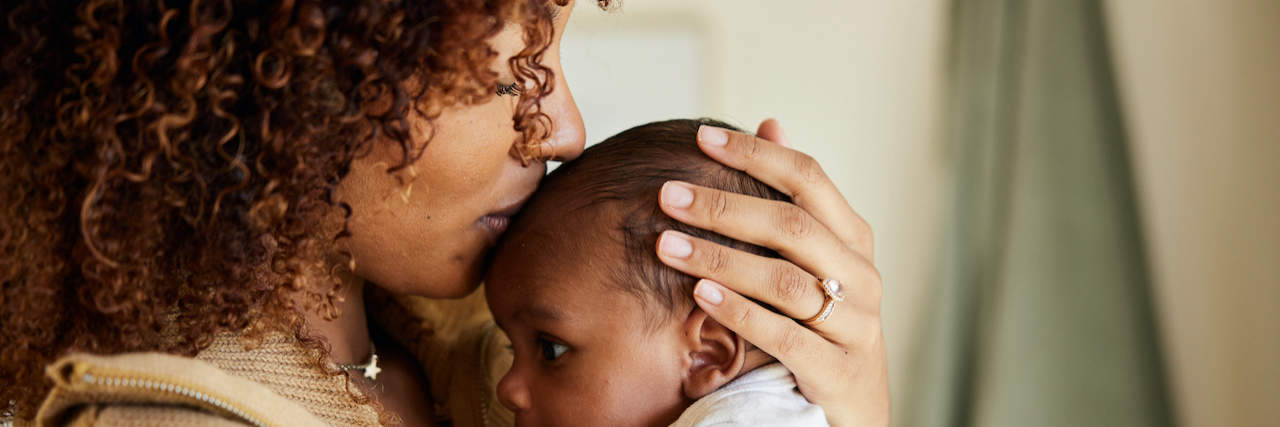 Becoming a Mom While Dealing With Schizoaffective Disorder Black mother holding and kissing baby on top of their head