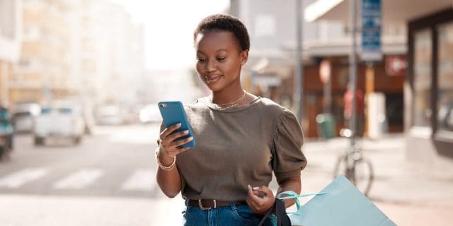 Shot of an attractive young woman using her cellphone outside while shopping in the city