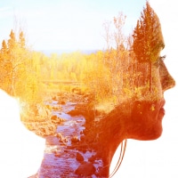 double exposure of a woman and a forest with a river at sunset