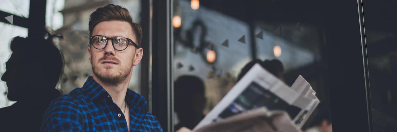 How a Four-Day Work Week Can Help With Burnout Man sitting outside at cafe reading the newspaper