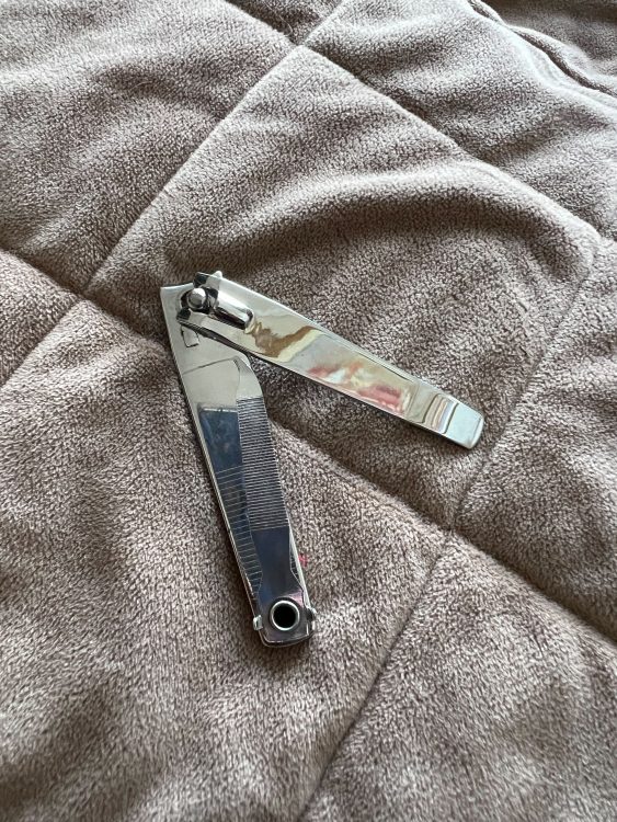 Silver nail clippers against a brown backdrop