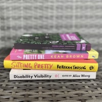 Spines of books: "Disability Visibility," "Sitting Pretty," "The Pretty One," and "Disfigured"