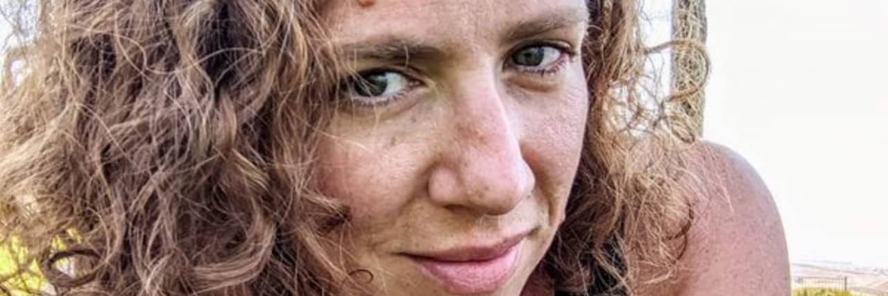 Advice for People Newly Diagnosed With Vasculitis or Chronic Illness The author, a woman with curly brown hair, lies on her stomach on the grass.