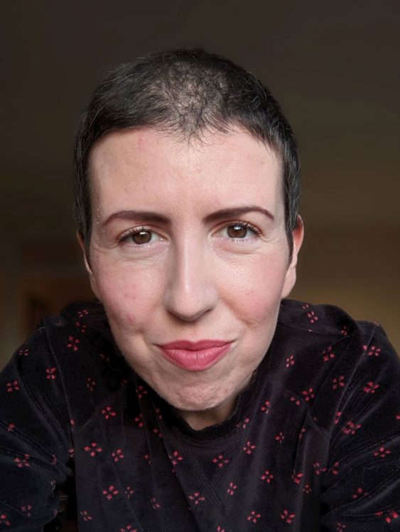 The author, a woman with short dark brown hair wearing a black shirt with a red pattern.