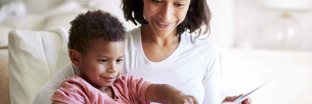 The Formula for Helping Children Cope With Big Feelings Woman of color reading a book with her son
