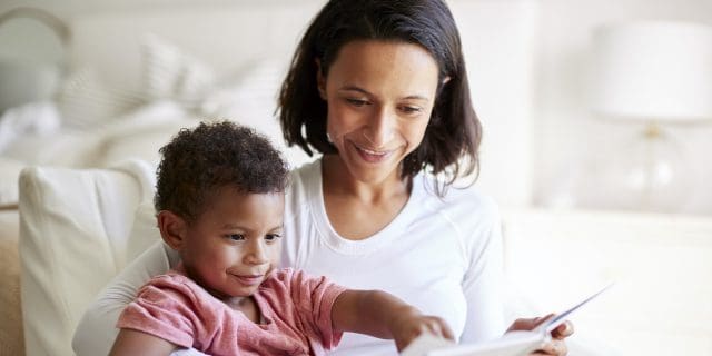 Woman of color reading a book with her son