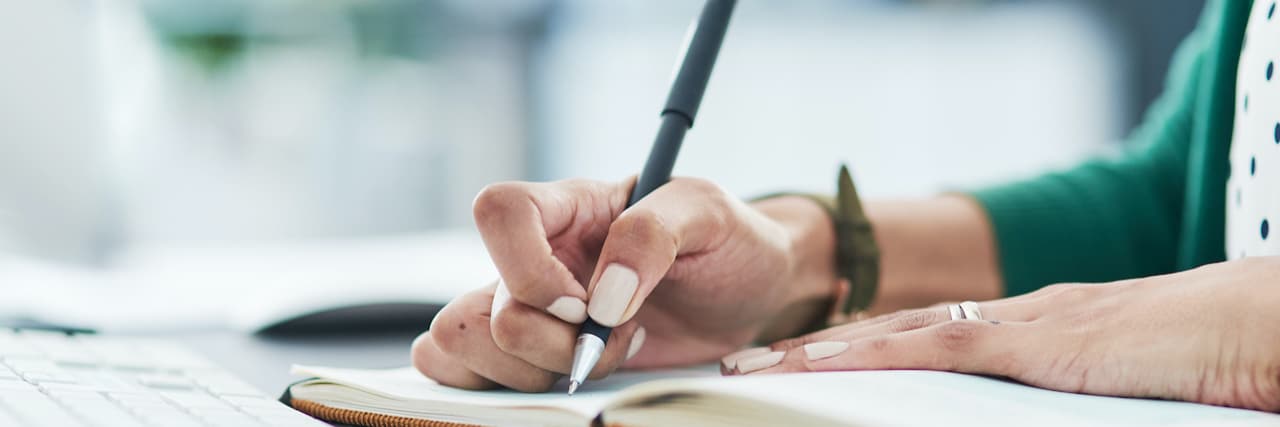 10 Reasons Why Writing Top 10 Lists Lifts My Mood With Depression Hand holding pen on paper in journal at desk