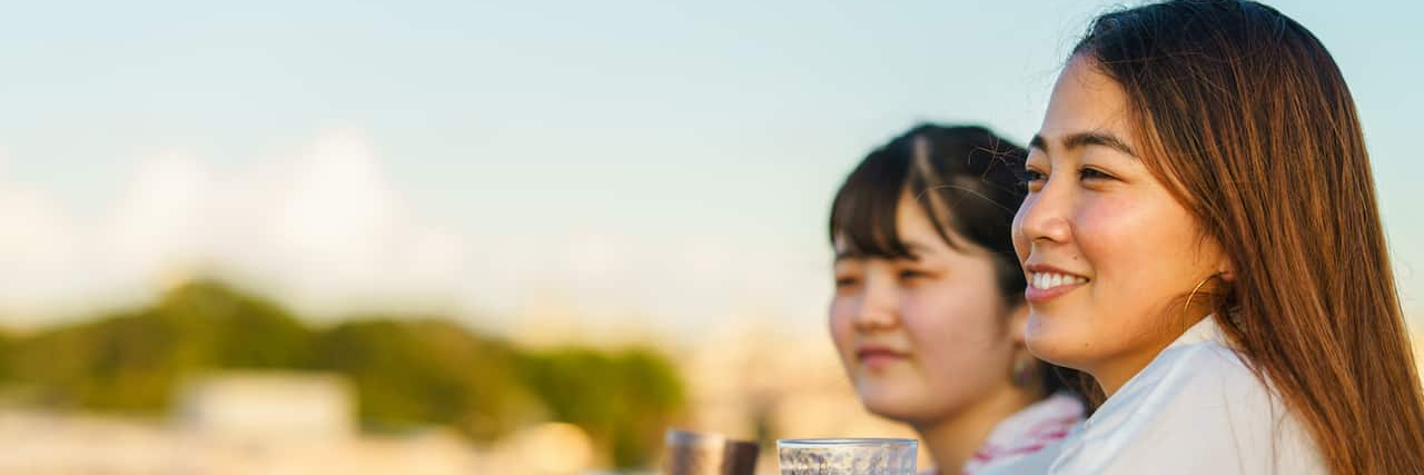 What Accepting Bipolar Disorder Means to My Sibling Relationship Two Asian women standing outside and smiling