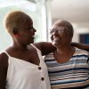 Black older mother and daughter embracing at home