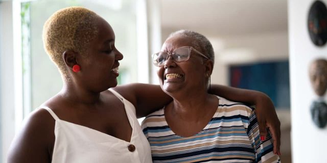 Black older mother and daughter embracing at home