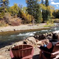 Contributor sitting on an adirondack chair next to beautiful river and trees