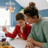 Mother and son in child's bedroom looking at workbook and holding a pencil