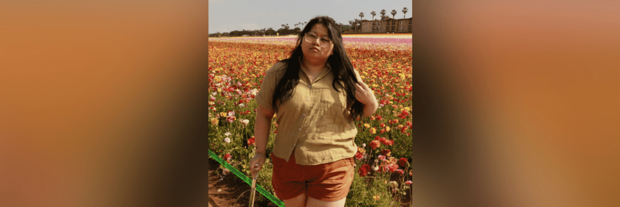 I Lived With Undiagnosed Migraine for 8 Years Image of contributor standing in front of field of flowers with a clear cane