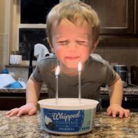 Image of contributor's son blowing out candles on a "cake" in a whipped cream tub