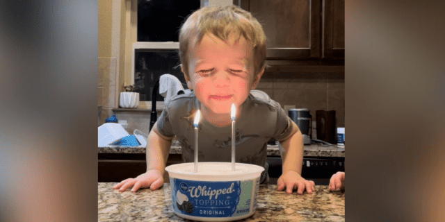 Image of contributor's son blowing out candles on a "cake" in a whipped cream tub