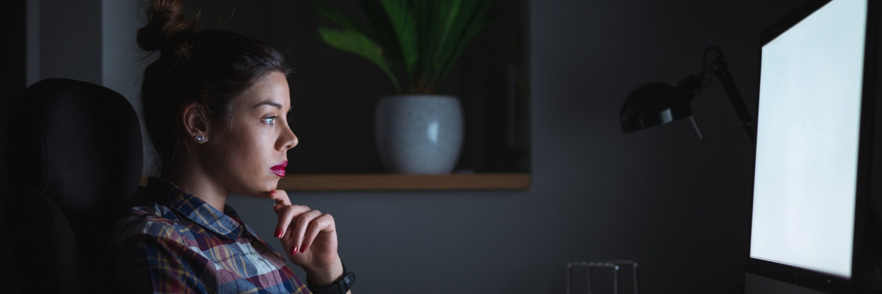 Tips for Returning to Work after a Mental Health Crisis Woman sitting and thinking in front of a computer in the dark