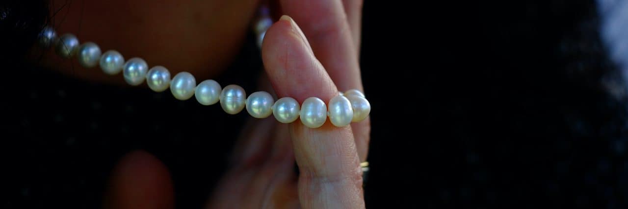 Close-Up Of Woman Holding Pearl Necklace