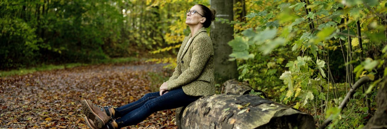 Capturing Moments and Living in the Present With Chronic Fatigue Syndrome Woman sitting on a tree trunk in a autumn forest
