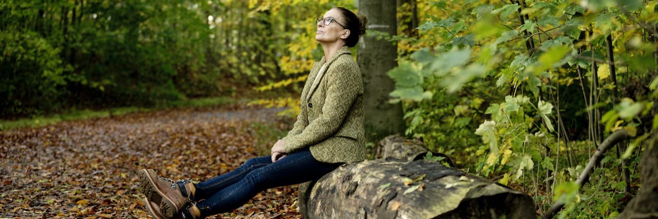 Woman sitting on a tree trunk in a autumn forest