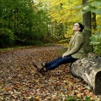 Woman sitting on a tree trunk in a autumn forest