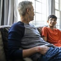 Father and son talking on couch at home