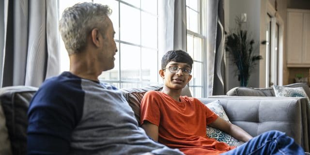 How to Talk to Your Child About Sex Father and son talking on couch at home