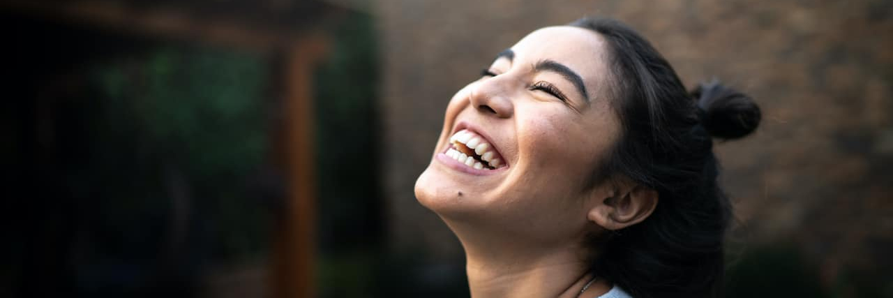 How Stimulating the Vagus Nerve Can Help Your Mental Health Woman smiling and looking up at the sky
