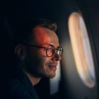 Man looking through plane window with sun on his face