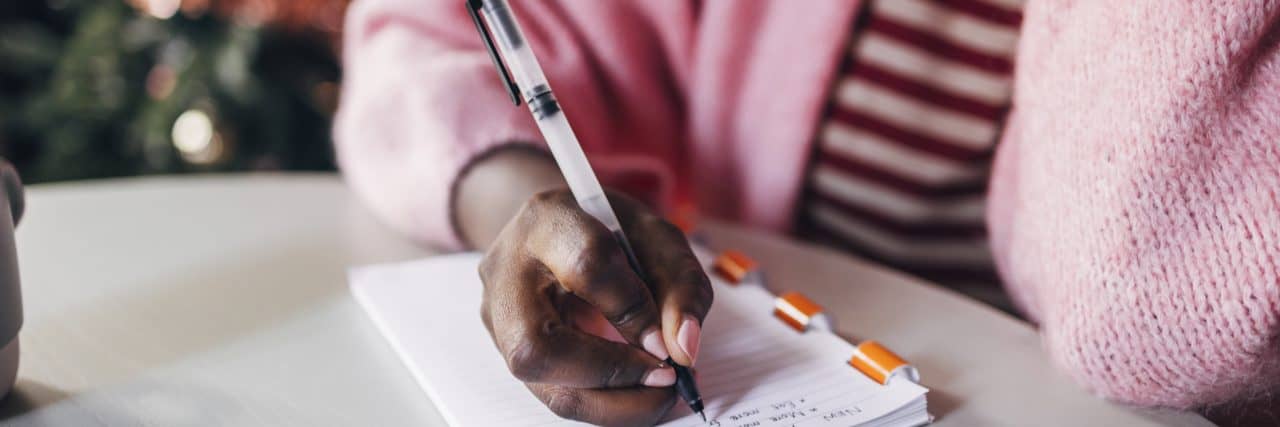 Close up shot of an anonymous black woman writing plan for a New Year on Christmas day.