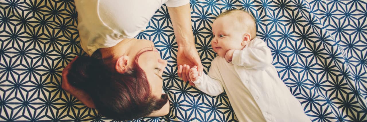 What Being a Mom Has Taught Me About UC Mother and baby girl lying on the bed together looking at each other.