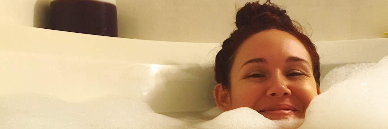 The Pros and Cons of Getting a Walk-In Bathtub for Chronic Pain Woman smiling in bath with head peeking out, surrounded by bubbles